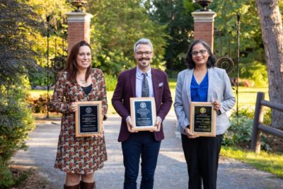 Three postdocs pose with their awards at the urn gardens near the Big Red Barn