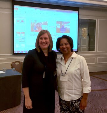 Two women in business casual dress at a conference presentation