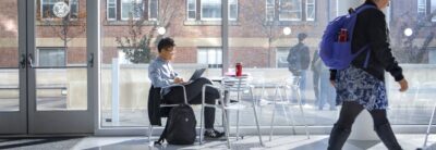 Scholar at a laptop in a physical sciences atrium