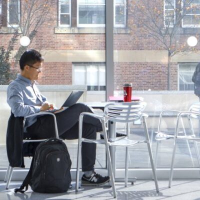 Scholar at a laptop in a physical sciences atrium